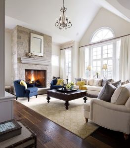 This beautiful room is flooded with amazing natural light.  It's architecturally detailed windows are framed with neutral draperies.  The natural furniture complements the contrasting coffee table, fireplace, drapery rod, accent chair and pillows.  The lighting fixture above provides a focal point bringing  your eye around the room.